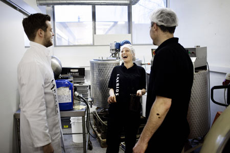 Lakridskongen Johan Bülow (i hvid kittel) samme med to ansatte på lakridsfabrikken